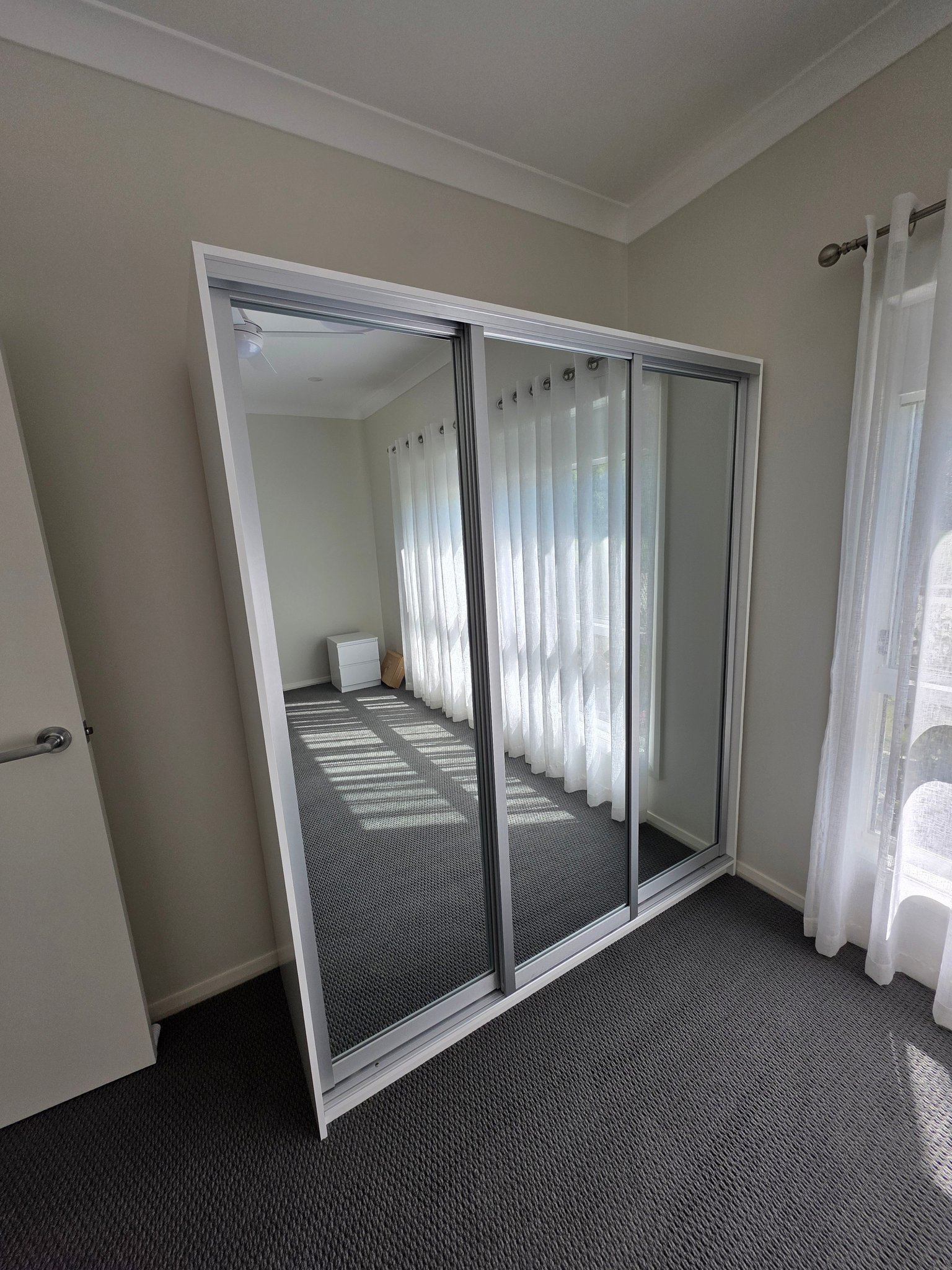 Mirrored sliding wardrobe fitted in a bedroom