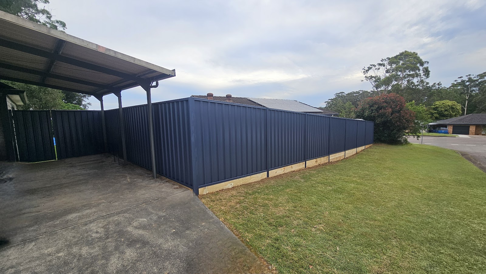 Long run of new fencing beside a carport